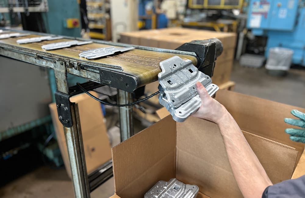 team member boxing freshly metal stamped auto parts