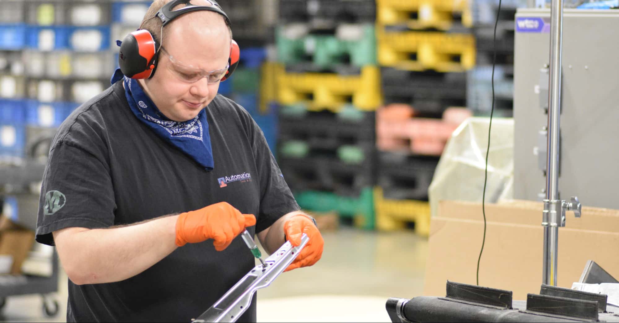 ATD technician inspecting stamped metal component to ensure precision and reliability for industrial hardware like durable fasteners & heavy-duty brackets